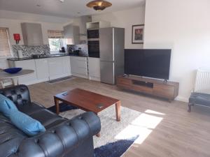 a living room with a couch and a table and a kitchen at Exeter Executive Apartments in Pinhoe +13 photos