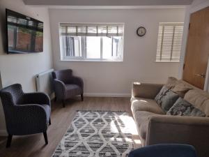 a living room with a couch and two chairs at Exeter Executive Apartments in Pinhoe