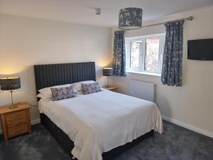 a bedroom with a bed and two lamps and a television at Exeter Executive Apartments in Pinhoe