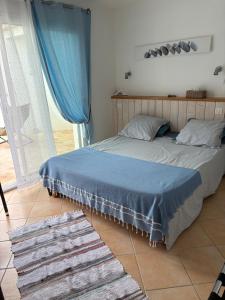 a bedroom with a bed with blue sheets and blue curtains at Chambre d'hôtes les Galets Bleus in La Rochelle