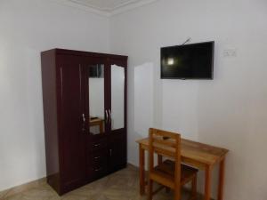 a room with a table and a television on a wall at Delhi Gardens Hotel in Fort Portal
