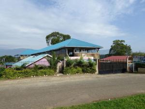 a house with a blue roof next to a street at Delhi Gardens Hotel in Fort Portal
