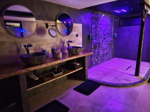 a purple bathroom with two sinks and a shower at L'Expérience in Villermain