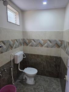a bathroom with a toilet and a window at AJS Elite Rooms in Nagari