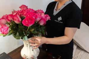 Eine Frau hält eine Vase mit rosa Rosen. in der Unterkunft Hotel Boutique Inca Real in Cuenca