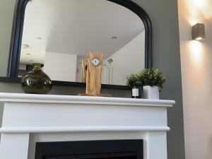 a mirror over a fireplace with a clock on it at The Canongate Coorie in Jedburgh