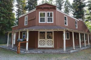 a large red house with a white garage at Wilderness West Resort Cabin 2 in Colville