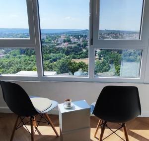 two chairs and a table in front of a large window at Gorgeous view apt riscanovca in Chişinău
