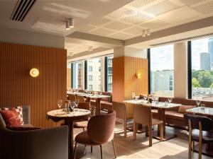 a restaurant with tables and chairs and large windows at Mercure Melbourne La Trobe Street in Melbourne