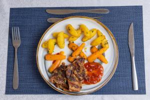 a plate of food with meat and vegetables on a table at Landmark Hotel Nanyuki in Nanyuki