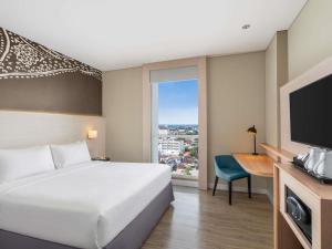 a hotel room with a bed and a desk and a television at Mercure Solo in Solo +15 photos