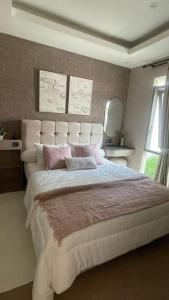 a bedroom with a large white bed with pink pillows at Ivory House in Gantungan