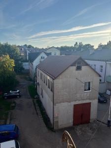 a small white building with a red door in a parking lot at Sia Rebir D, Hotel Rebir in Daugavpils