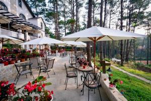 a patio with tables and chairs with umbrellas and flowers at De Vivre Homestay Măng Đen in Kon Von Kla