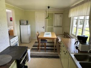 eine Küche mit einem Tisch und einem weißen Kühlschrank in der Unterkunft Olles in Vessigebro
