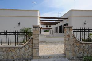 een gebouw met een hek en een stenen muur bij Carmelina 3 in Marina di Pescoluse