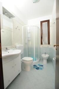 een badkamer met een douche, een toilet en een wastafel bij Carmelina 3 in Marina di Pescoluse
