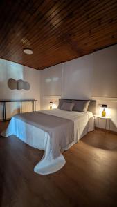 a bedroom with a large white bed with two lamps at Casa da Cerca in Cenlle