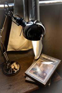 a desk with a lamp and a magazine and a book at Il Ciabattino di Ceva in Ceva