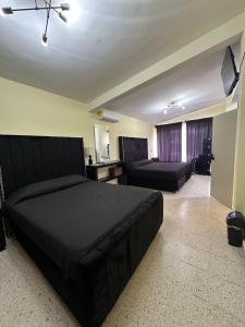 a bedroom with a large black bed and a couch at Hotel H Galería Club in Tuxtla Gutiérrez +16 photos