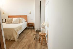 a white bedroom with a bed and a chair at Apartaments Bellreguard in Papiol
