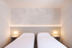 Zwei Betten in einem kleinen Zimmer mit weißen Wänden in der Unterkunft Hotel Eden in Sistiana