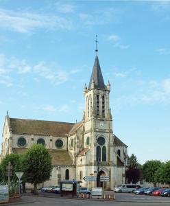 eine Kirche mit einem Turm, auf dem eine Uhr angebracht ist in der Unterkunft Zéline in Montholon