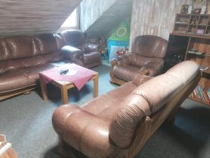 a living room with brown leather couches and a table at ANEMA Ferienwohnung in Bayerisch Eisenstein