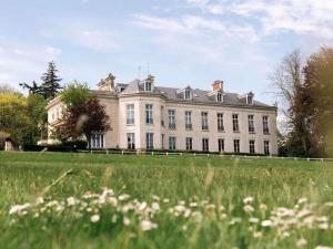 a large white building with a grass field in front at Hotel Novotel Domaine de Maffliers - Paris Val-d'Oise in Maffliers