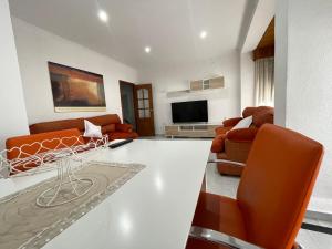 a living room with orange chairs and a couch at Apartamento CASA EL MORABITO in Puente Genil