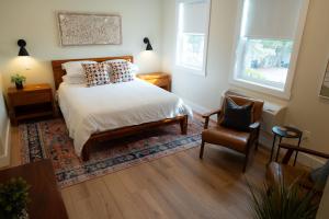 a bedroom with a bed and a chair and two windows at The Cove Inn in Westport +46 photos