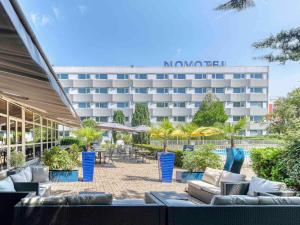 a hotel with chairs and tables and a building at Novotel Paris Nord Expo Aulnay in Aulnay-sous-Bois