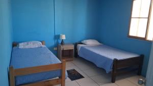 a room with two beds and a blue wall at Hostal Mejillones in Mejillones