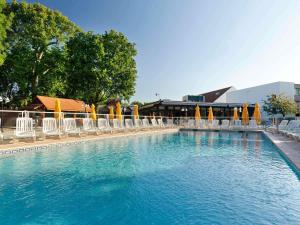 a large swimming pool with chairs and umbrellas at Novotel Saclay in Saclay