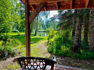 a porch with a bench and a view of a pond at Denali Fireside Cabin & Suites in Talkeetna