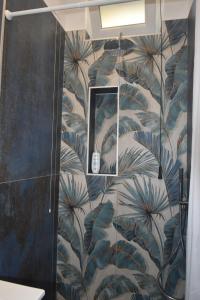 a bathroom with a shower with blue and green leaf wallpaper at AzzurroMare Ponza Rooms Sea View by Caseaponza it in Ponza