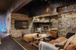 a living room with a stone wall with a fireplace at Cozy Mountain Beito - 18 sengeplasser - bilijard in Beitostøl