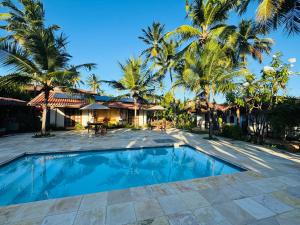 a swimming pool in front of a house with palm trees at Pousada Vila Icaraí in Icaraí