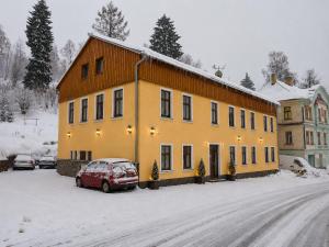 a yellow building with a car parked in the snow at Penzion Na Rozcestí in Janov nad Nisou