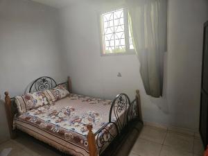 a small bed in a room with a window at Villa route ourzazate in Aït Ourir +4 photos