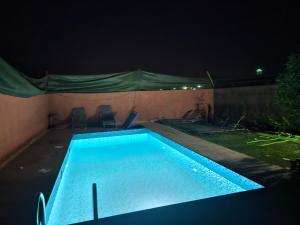 a swimming pool at night with two chairs around it at Villa route ourzazate in Aït Ourir
