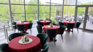 a room with red tables and chairs and windows at Hotel Nord in Ploieşti