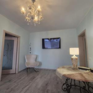 a living room with a chandelier and a table and a chair at Apartament Stephen in Constanţa