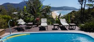 a swimming pool with chairs and a view of the beach at Suíte Vista Mar Praia Estaleiro Balneário Camboriú in Balneário Camboriú