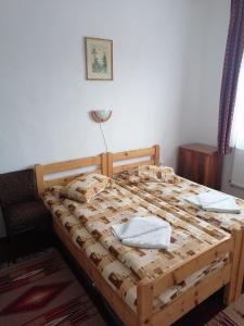 a bedroom with a wooden bed with two towels on it at Sófalvi Vendégház in Sîntimbru