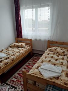 two twin beds in a room with a window at Sófalvi Vendégház in Sîntimbru