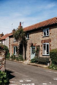 a brick house with a bench in front of a street at Staneve Cottage in Docking