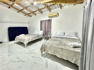 a bedroom with two beds and a stone floor at Mi Refugio 3 in Río San Juan