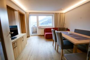a room with a dining table and a living room with a window at Soldanella in Lech am Arlberg