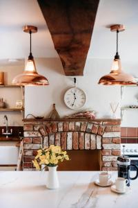 a kitchen with a brick fireplace with a clock on the wall at Staneve Cottage in Docking